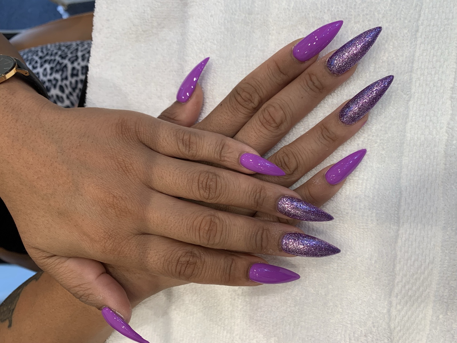 Long stiletto nails in glossy purple with purple glitter accent nails