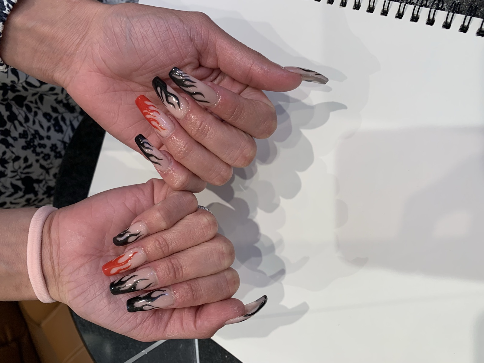 Coffin nails with a nude base and black flame tips, plus red and orange accent flames
