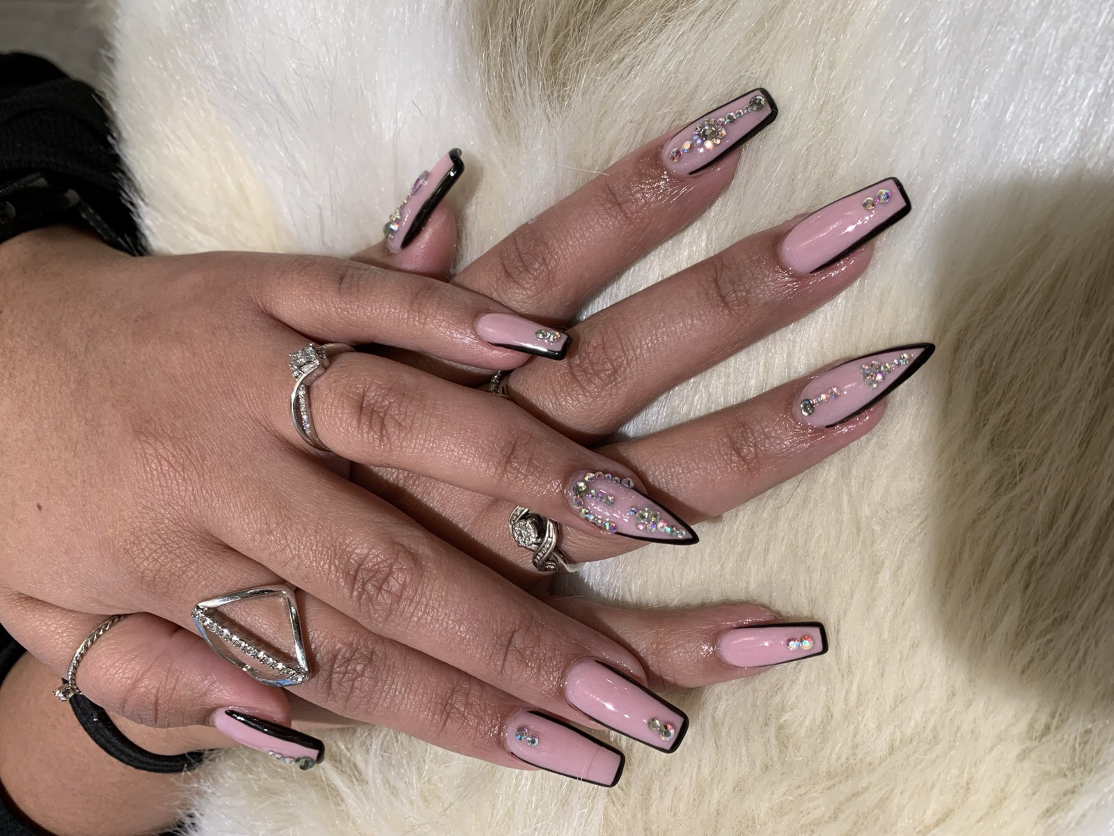 Long pink nails with black outlines and rhinestone accents