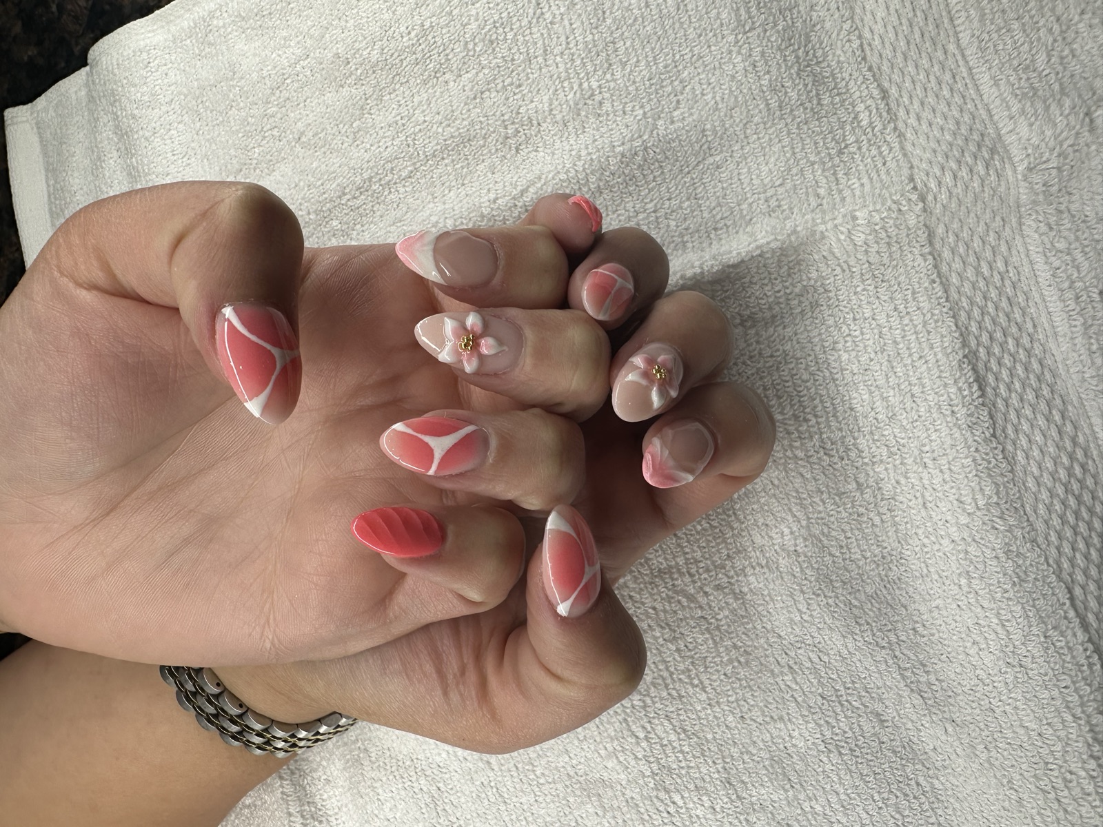 Almond nails with coral, white marble, and 3D floral accents