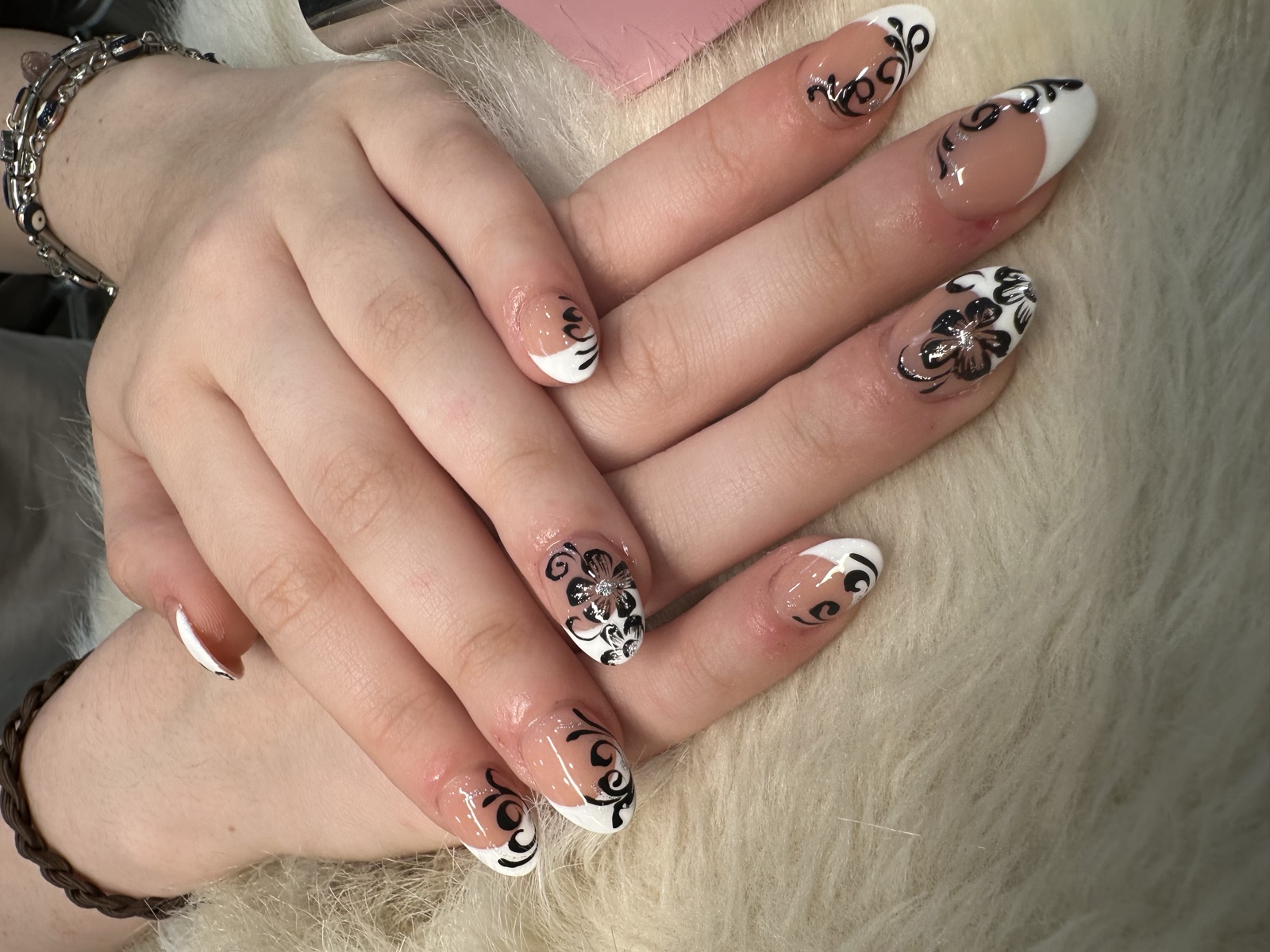Almond French tips with black floral swirl nail art and rhinestones