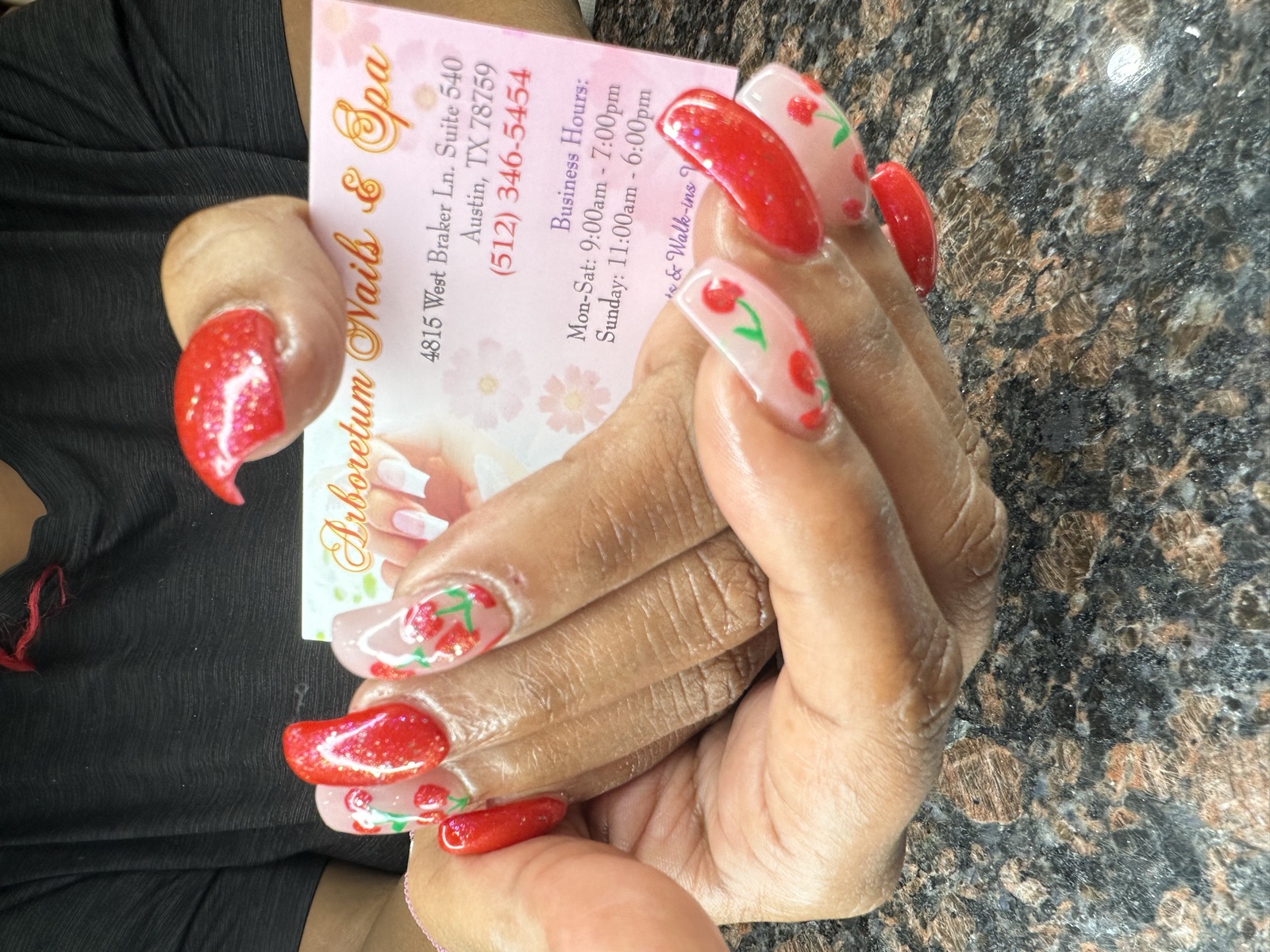 Square nails with glittery red polish and painted cherry designs