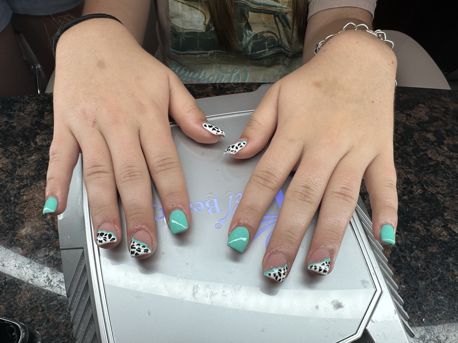 Short square nails in mint green with black-and-white spotted accent tips