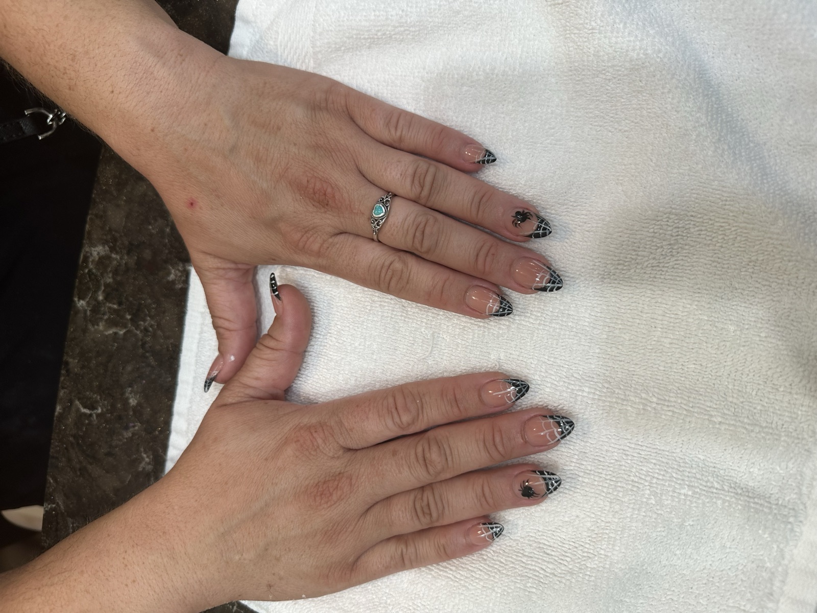 Stiletto nails with black French tips, spiderwebs, and spider accents